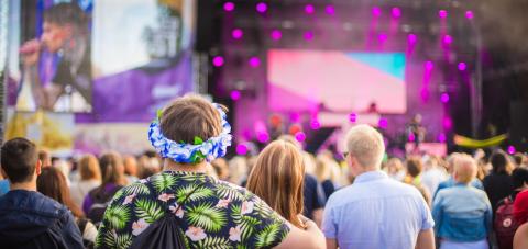 At the front there's audience and at the back there's the stage with purple lights.