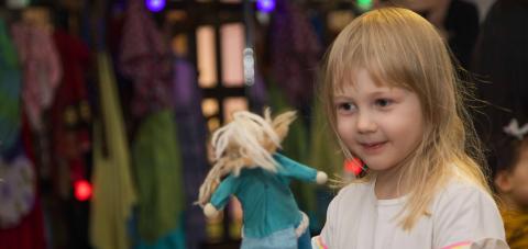 Vaaleatukkainen tyttö leikkii sinisellä merenneito-kurkistusnukella.