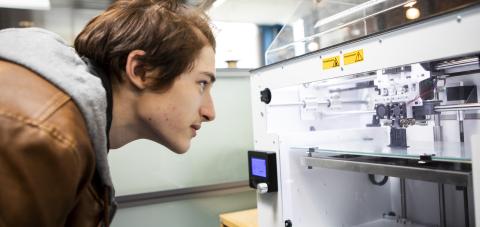 Opiskelija katsoo 3d-tulostinta.