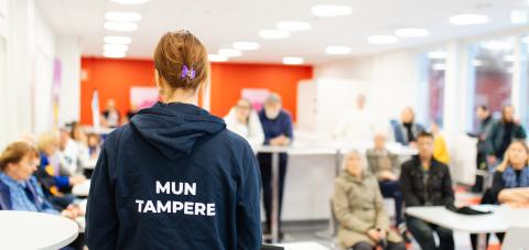 Mun Tampere -huppariin pukeutunut kaupungin työntekijä on yleisön edessä keskustelemassa heidän kanssaan.