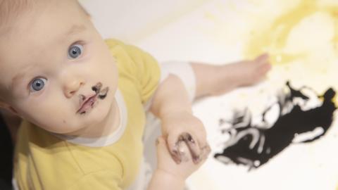 Vauva maalaa mustalla värillä taideteosta.