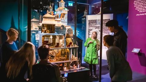 Ihmisiä ja opas Muumi-talo kuvaelman ympärillä Muumimuseossa.