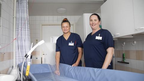 Koukkuniemen lähihoitajat suihkutuspisteessä. Kuvassa myös apukädeksi kutsuttu laite.