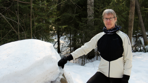 Henkilö metsässä kiven vieressä. Pia Nykänen.
