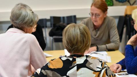 Henkilöt istuvat pöydän ääressä ja opiskelavat.