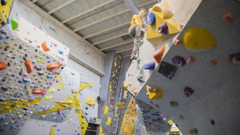 Henkilö kiipeilee boulder-seinällä.