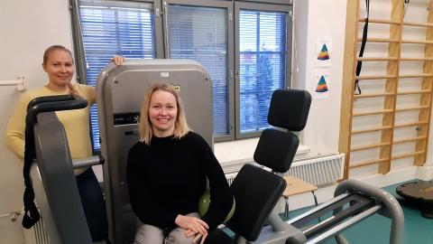 Kaksi hymyilevää fysioterapeuttia on kuntosalilla.