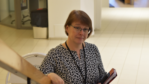 Henkilö seisoo portaikossa kansio kädessään.