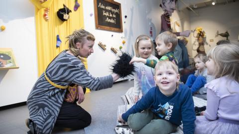 Ohjaaja leikittää lattialla istuvaa lasten ryhmää