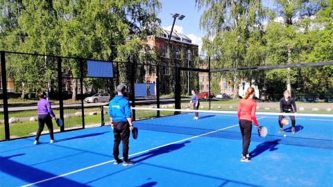 Nuoret pelaavat padelia liikunnanohjaajan kanssa.