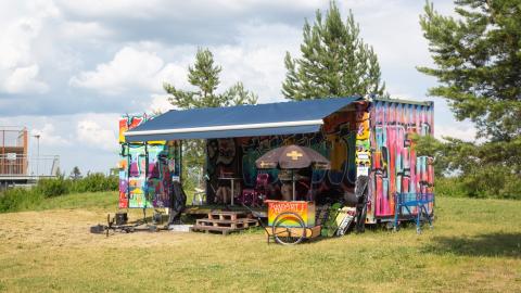 Graffitelilla kotisteltu työmaakontti kesäisessä skeittipuistossa.