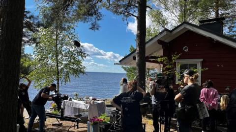 Kuvausryhmä tekee työtään kesäisen järven rannalla tv-sarjan kuvauksissa.