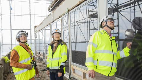 Kolme rakennsuvalvojaa tutkii valkoisen talon vieressä ikkunoita ja seinämateriaaleja.