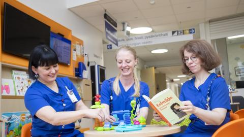 Three early childhood education teachers are sitting around the table and planning the program for children.istuu pyöreän pöydän ympärillä