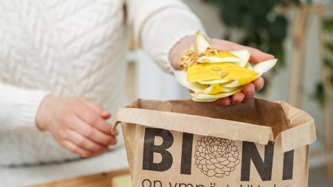 Asukas laittaa hedelmäjätettä paperiseen biojätepussiin.