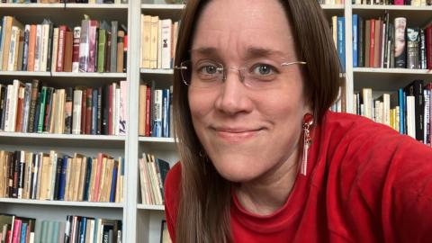 Henkilö istuu kirjastosalissa ja katsoo kameraan.