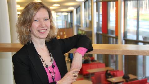 Henkilö nojaa kaiteeseen. Taustalla näkyy kahvila.