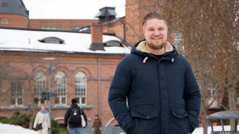 Henkilö seisoo ulkona talvisessa säässä ja katsoo kameraan.