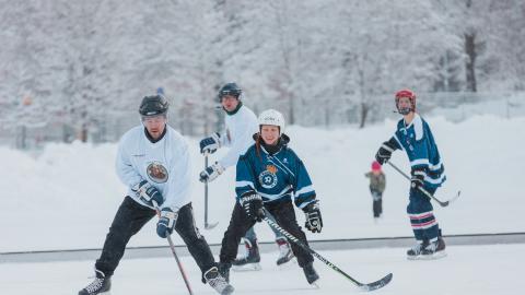 Four people playing hockey on ice.