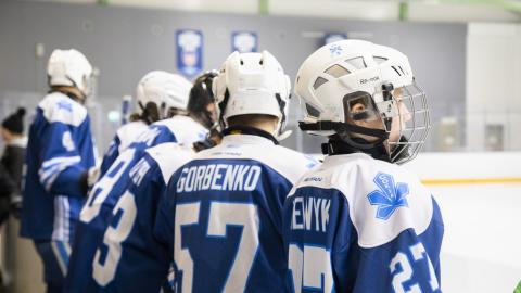 Nuoret jääkiekkoilijat katsovat jäälle.