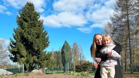 Vanhempi ja lapsi halaavat toisiaan keväisessä puistossa.