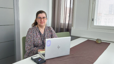 Terhi Lehtinen istuu pöydän ääressä ja pöydällä on kannettava tietokone