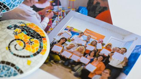 Two photographs of people on the table. There is also a colorful ceramic piece on the table.