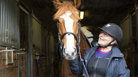 Sari Maunula is at the stables holding onto horse's halter.