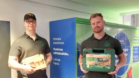 Two persons holding Mölkky and a cordless drill in their hands.