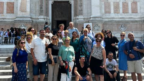 A group of people is standing on the steps of an old building.
