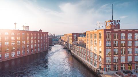 Tammerkoski virtaa kahden vanhan, punatiilisen ja ruutuikkunaisen tehdasrakennuksen välistä Tampellassa.