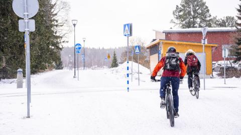 Pyöräilijät pyöräilevät talvisessa säässä.