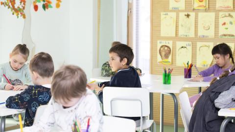 Pre-school pupils work on tasks at their desks.