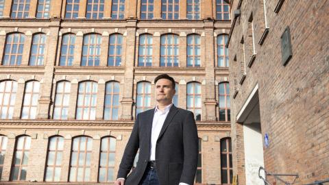 Henkilö seisoo Frenckellin ja Finlaysonin Siperia-rakennuksen välisellä aukiolla vieressään ja takanaan punatiilisiä rakennuksia.