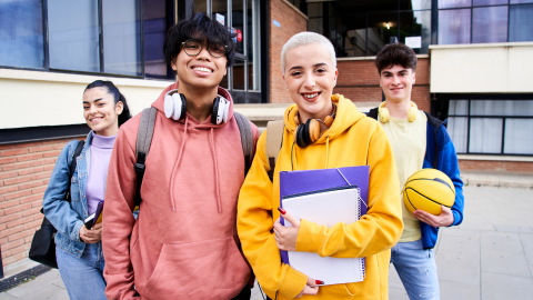 Neljä rennosti pukeutunutta nuorta koulun pihalla.