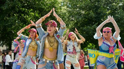 Colourfully dressed women dancing with their hands over their heads.