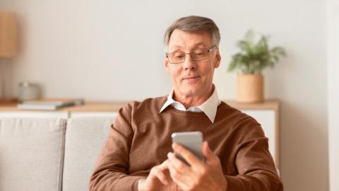 A person is sitting on a sofa and browsing on their smartphone.