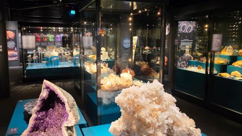 Hämärässä näyttelytilassa kiviä vitriineissä sekä jalustoilla.