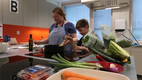 Aikuinen ja lapsi valmistavat kasvisruokaa kotitalousluokan keittiössä.