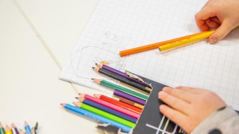 The child is handling crayons.