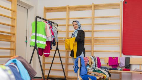 Sumaya Haidarian pitelee käsissään vaatteita ja hänen vierellään on penkki ja vaaterekki..