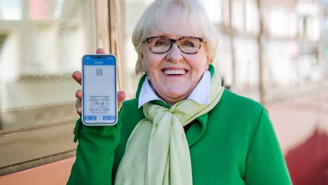 Nainen näyttää puhelimestaan mobiililippua ratikan edessä.