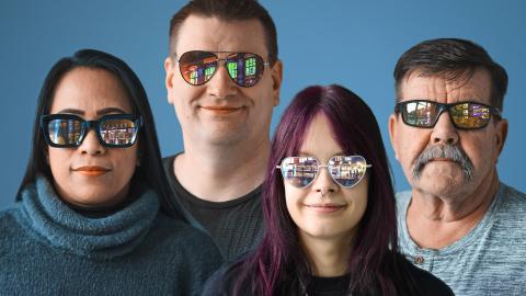 Neljä erilaista ihmistä katselee kohti. Heistä kaikilla on aurinkolasit, joista heijastuu erilaisia kaupunkiin liittyviä näkymiä.