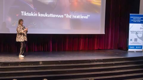 Tilaisuuden puhuja seisoo esiintymislavalla pitämässä koulutusta.