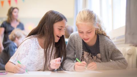 Two young people sits together in the classroom.