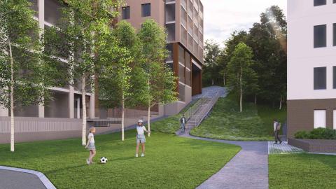 Lapsia pelaamassa palloa nurmella, taustalla kerrostaloja ja portaat rinteeseen.