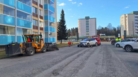 Harjaustraktori ja autonsiirtoauto parkkialueen puhdistyössä.