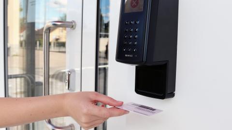 Asiakas pitää kirjastokorttia omatoimikirjaston lukijassa. 