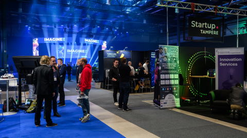 Ihmisiä seisoo tapahtuman messuosastolla.