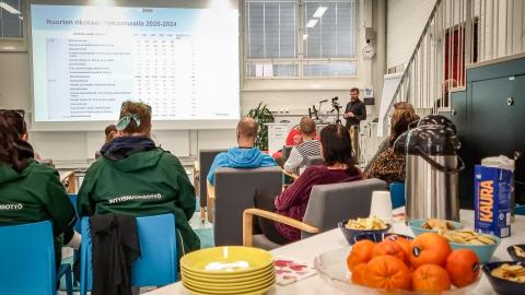 Yleisö istuu selin kameraan ja kuuntelevat luentoa.